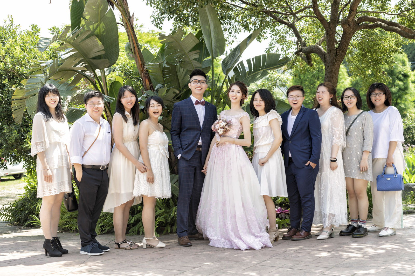 戶外婚禮現場，新人與賓客在綠意中自然合照