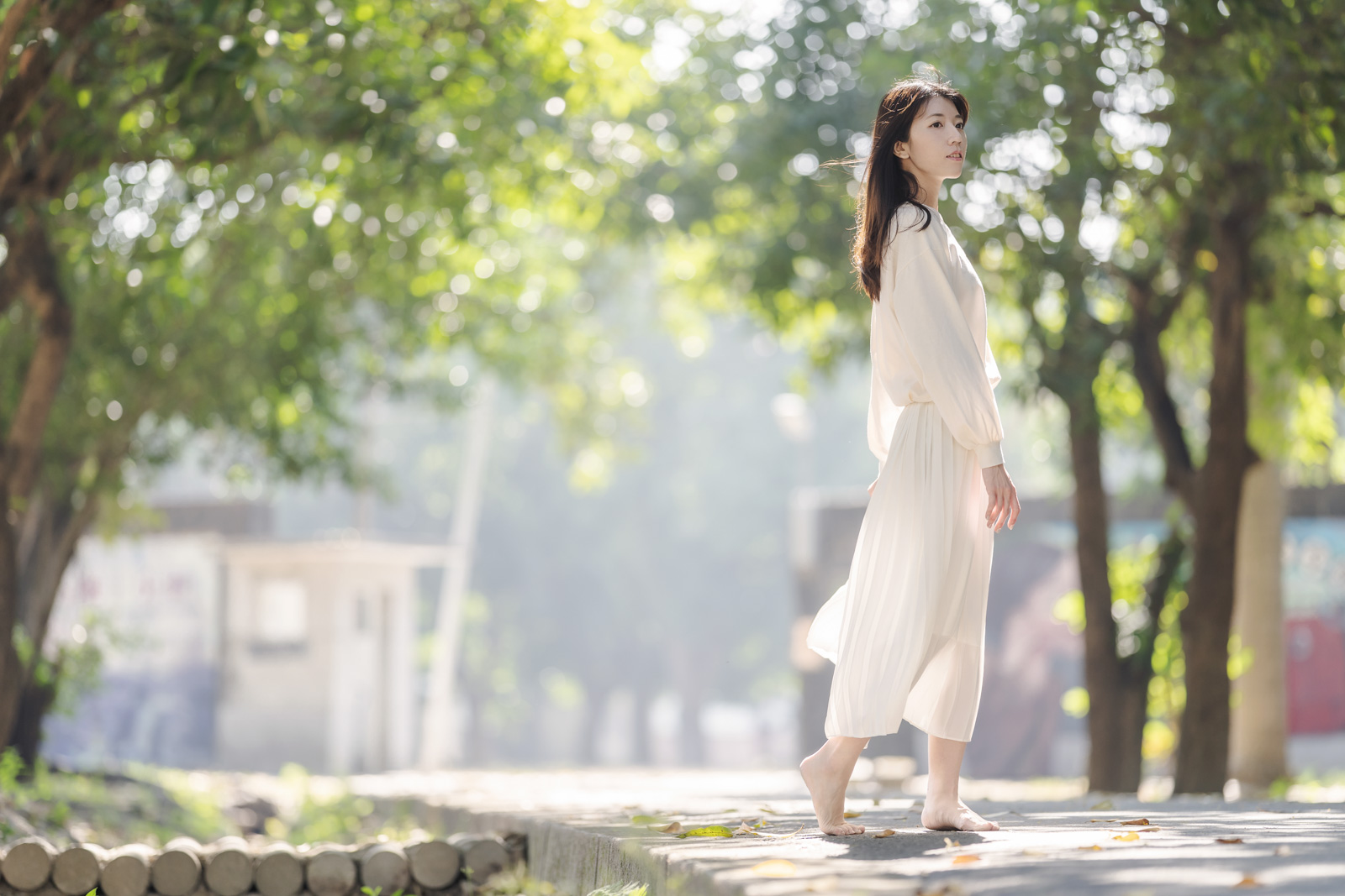 女子在陽光灑落的樹蔭下赤腳漫步