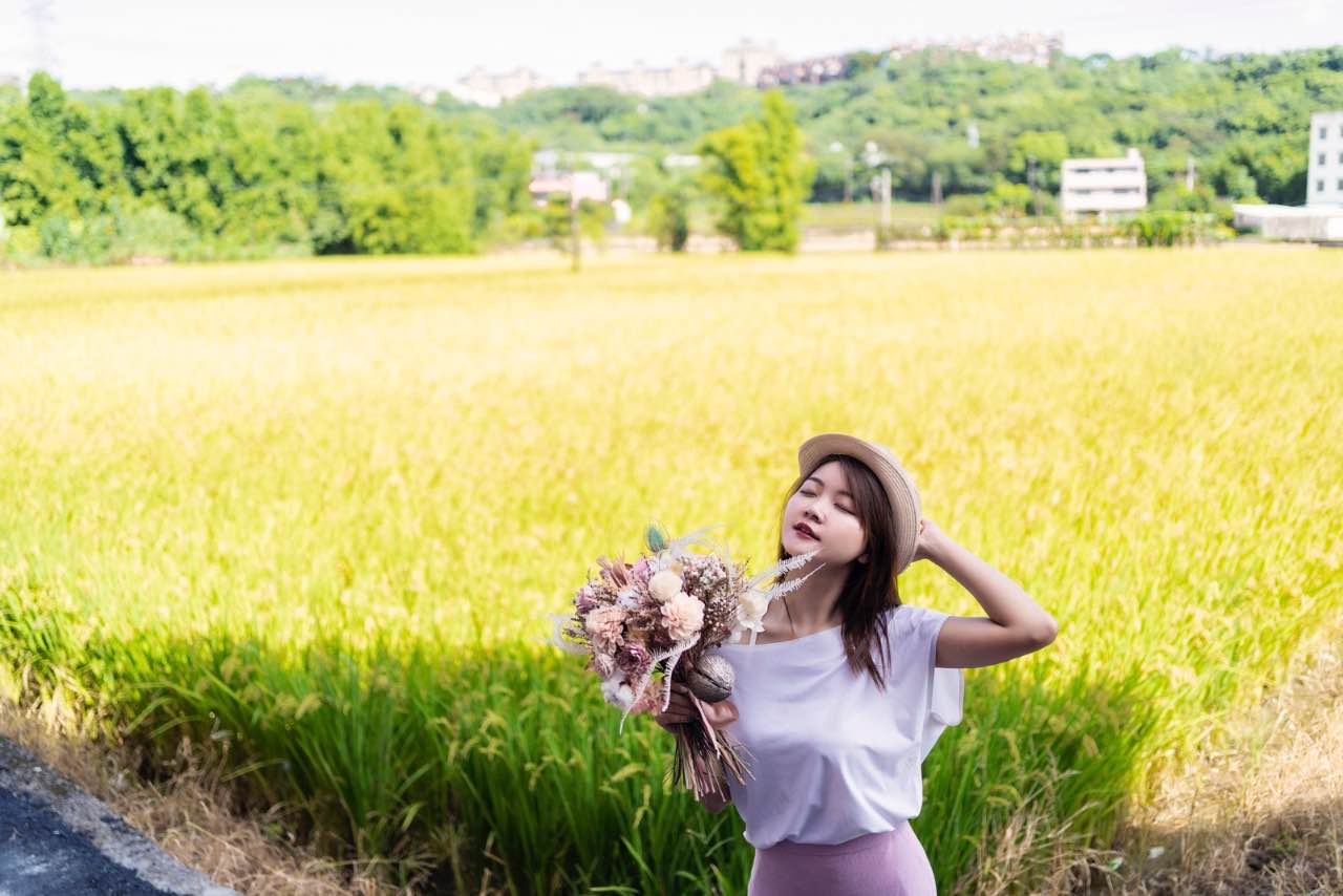 女子站在稻田前享受陽光的畫面
