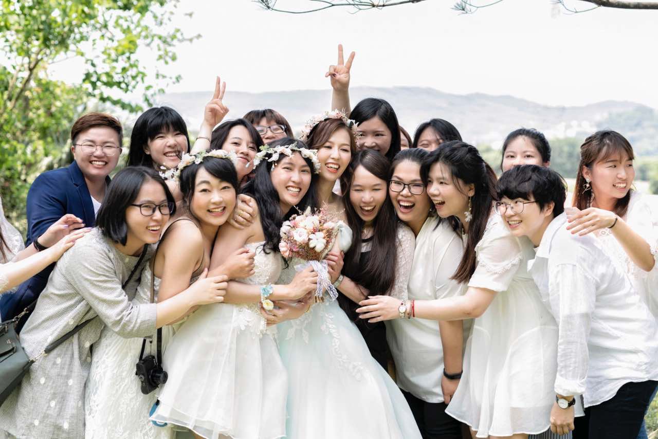 新娘與參與接捧花活動的女性賓客開心圍拍的瞬間。