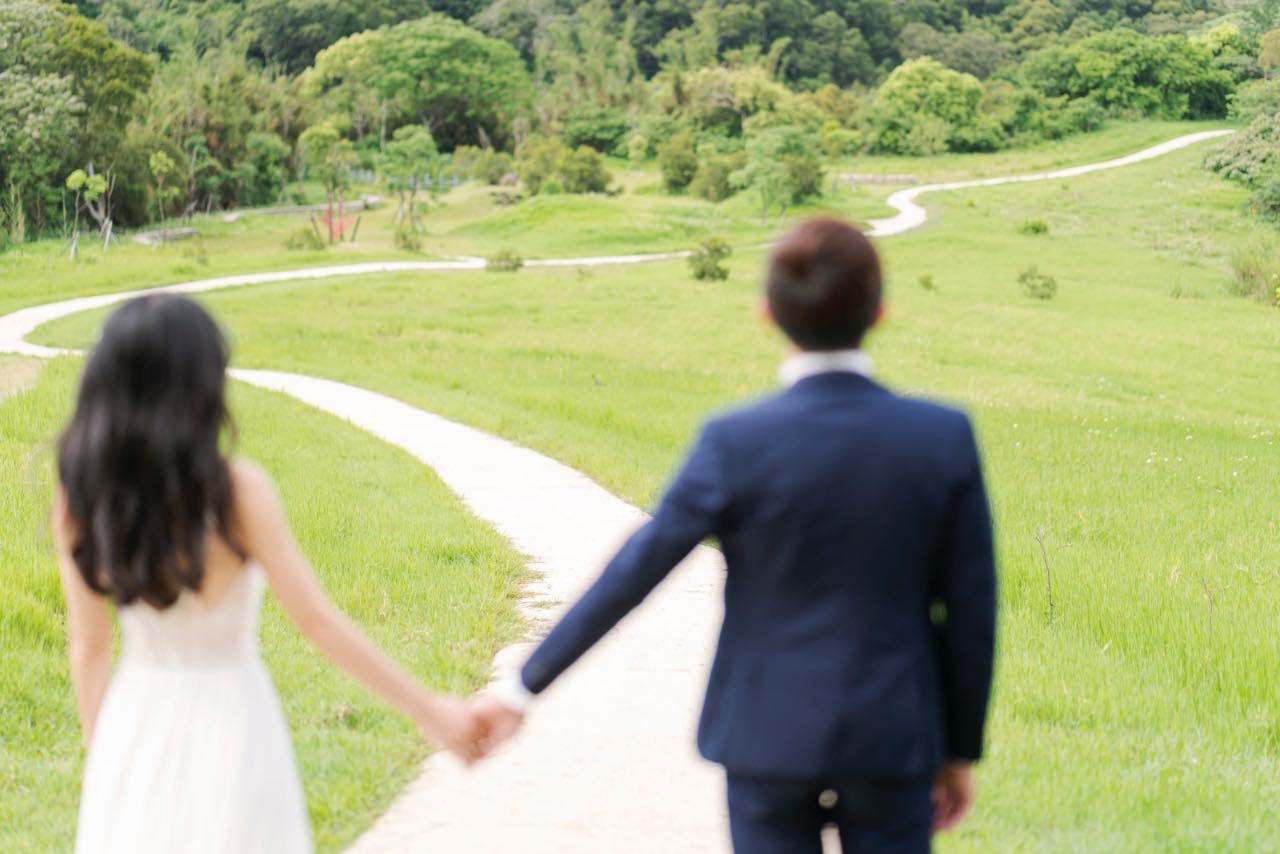青青草原牽手走向彎曲小徑的婚紗照