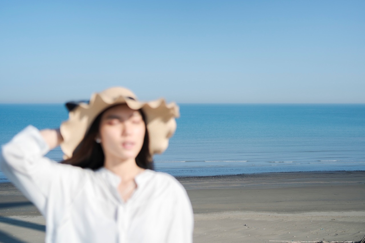 模糊前景中的模特與清晰的藍色海面形成對比