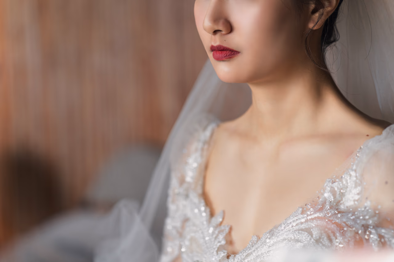 新娘化妝完成後的特寫，柔和光線從窗邊灑落，襯托出婚紗細節與優雅氣質。