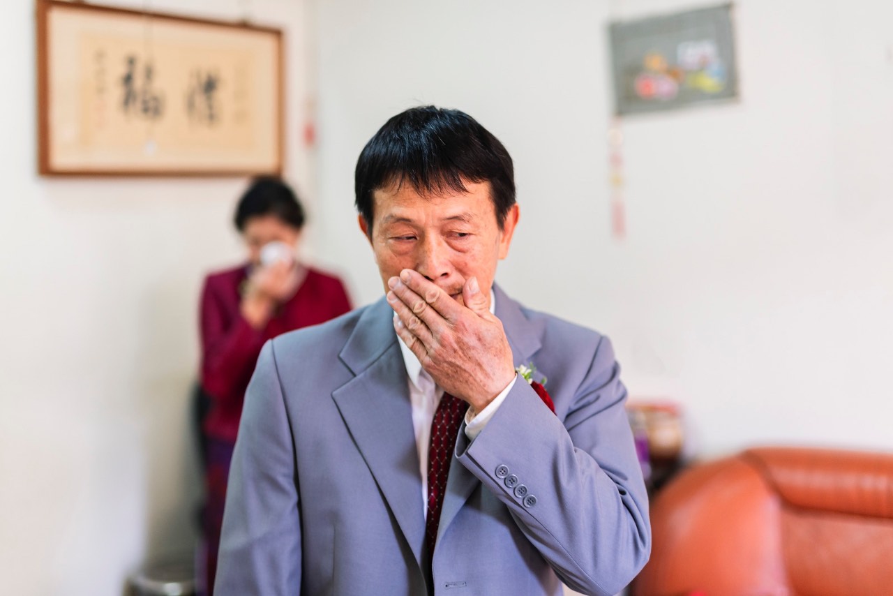 新娘父親情緒激動掩面落淚，母親站在後方默默拭淚