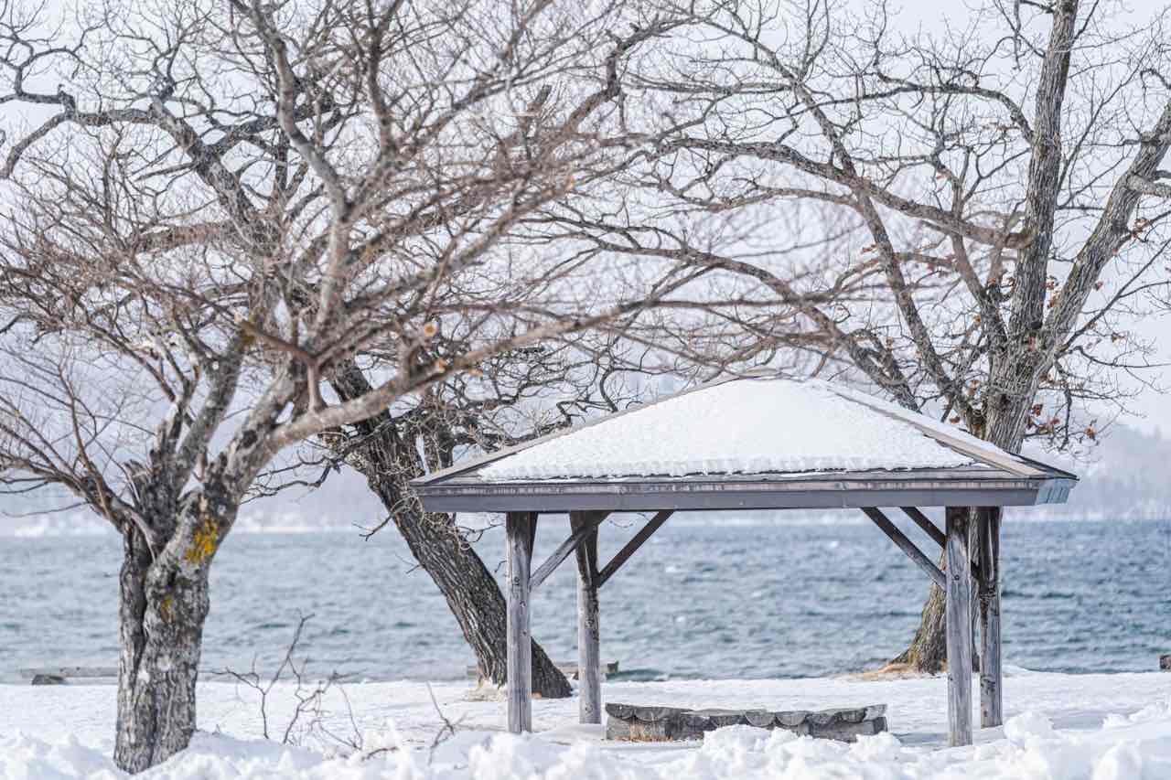 冬季湖邊的木造涼亭與雪景