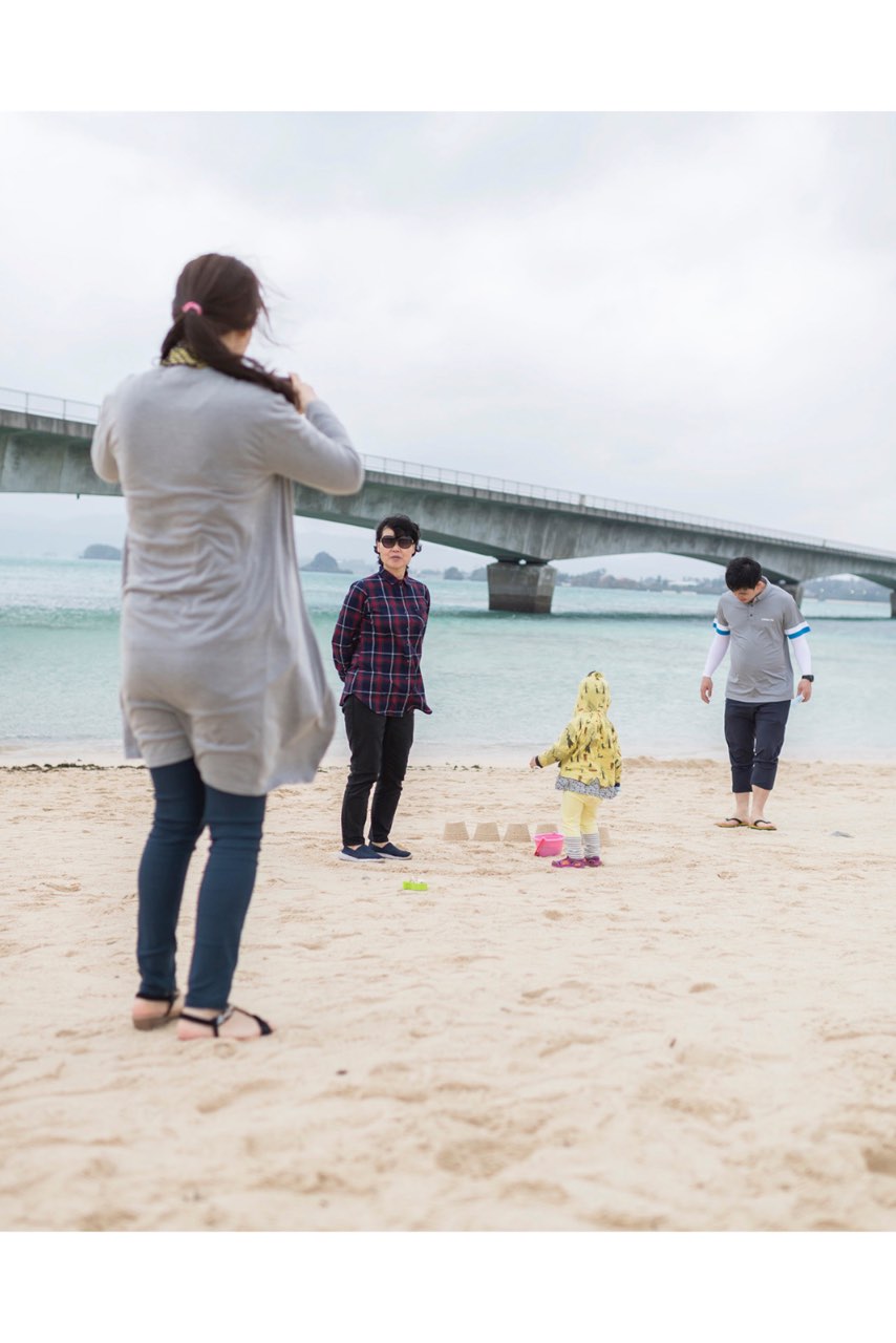 沖繩古宇利大橋旁的沙灘上,一家人隨興散步與遊玩,畫面自然帶有旅行氣息