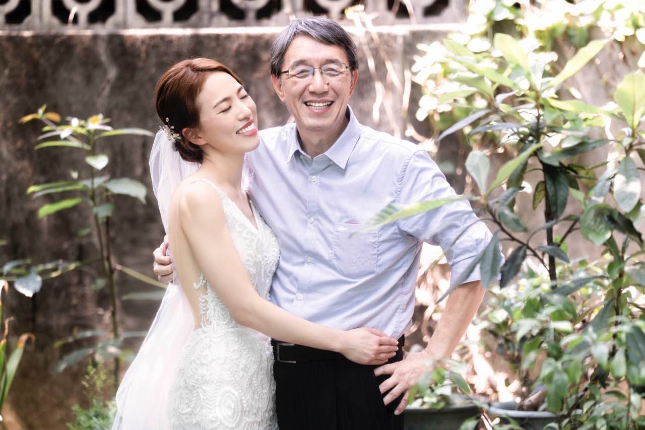 新娘與爸爸相擁微笑,站在自家庭院中合影