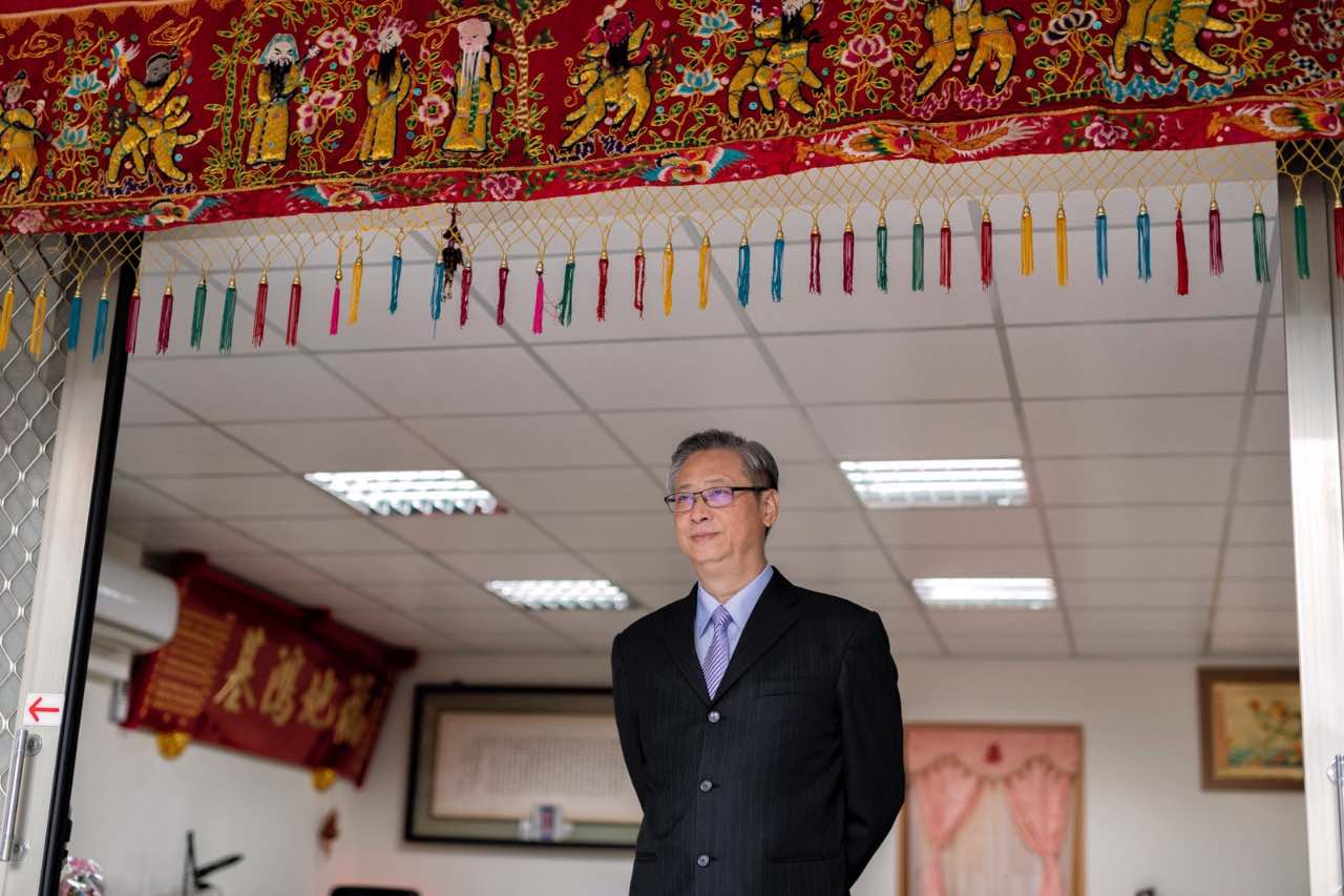 父親穿著西裝站在家門口,眼神溫和、神情沈穩