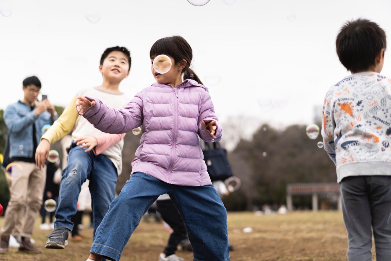 公園裡小孩奔跑追逐泡泡的瞬間