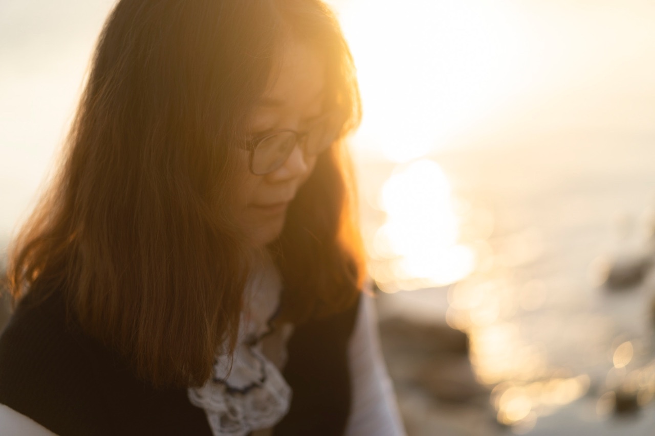 夕陽下的逆光人像，女性自然表情側拍