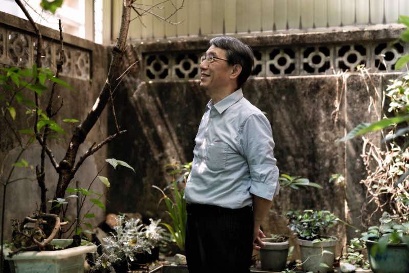 爸爸站在庭院光影中獨自思考，表情平靜自然