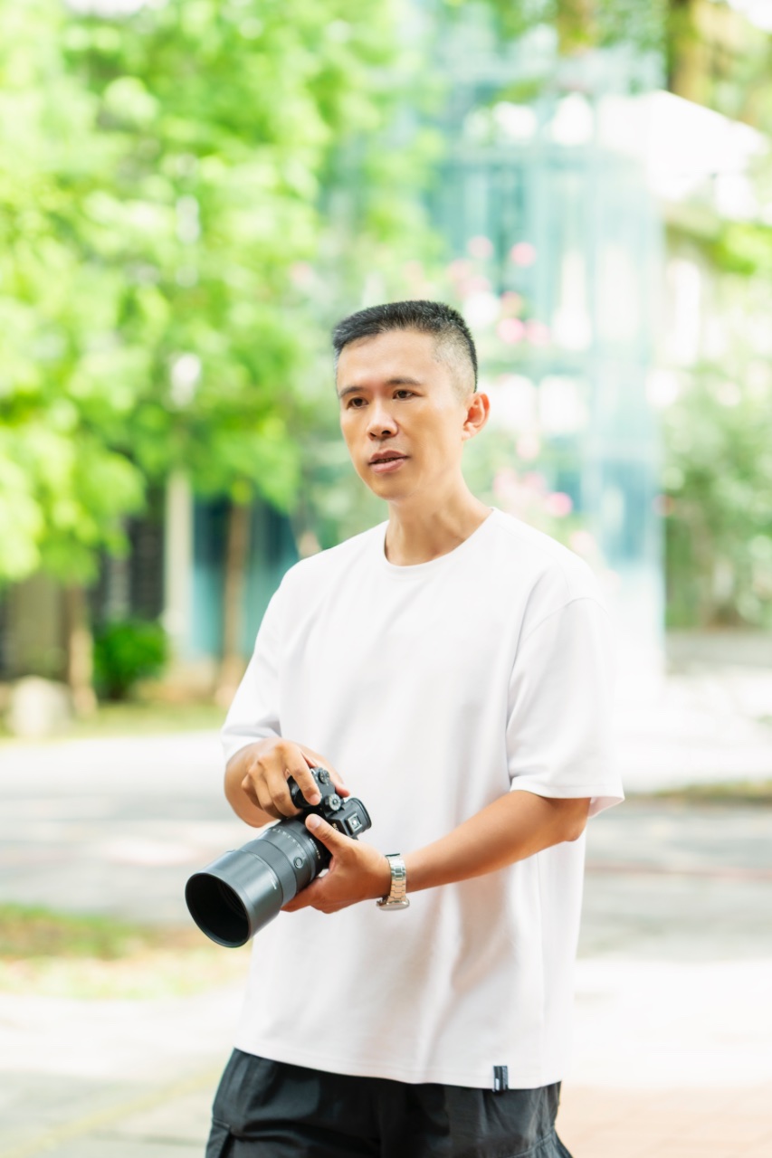 攝影師 Zach 手持相機站在戶外自然光下的形象照