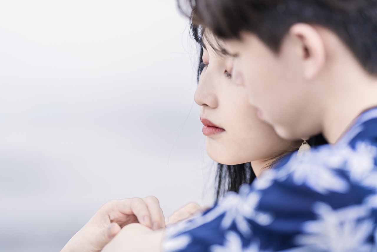 新竹新月沙灘情侶寫真,女生側臉特寫,男生在旁守護的親密氛圍