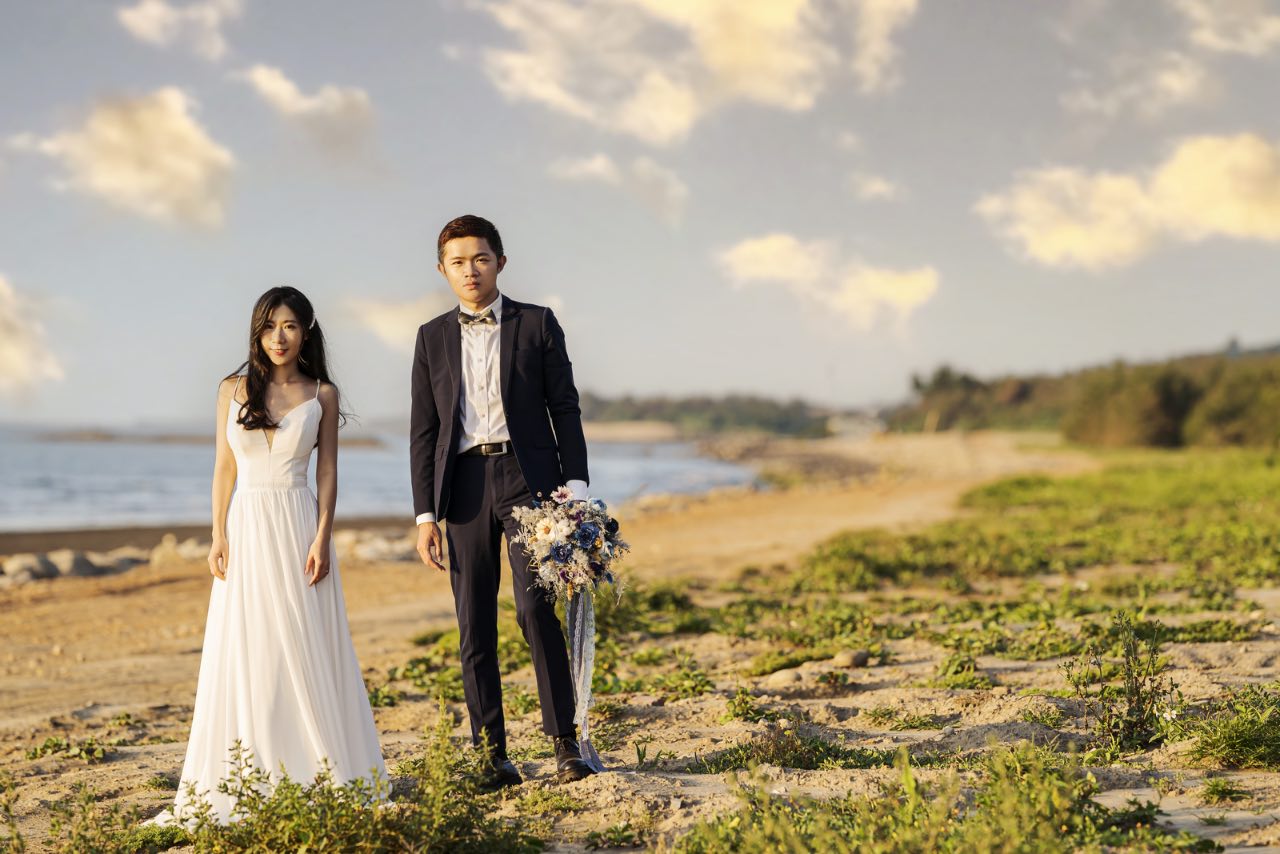 新竹新月沙灘婚紗攝影,新人並肩站在海岸上,新郎手拿花束