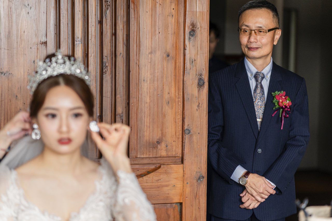 父親在門邊凝視正準備的新娘，神情溫柔沉穩