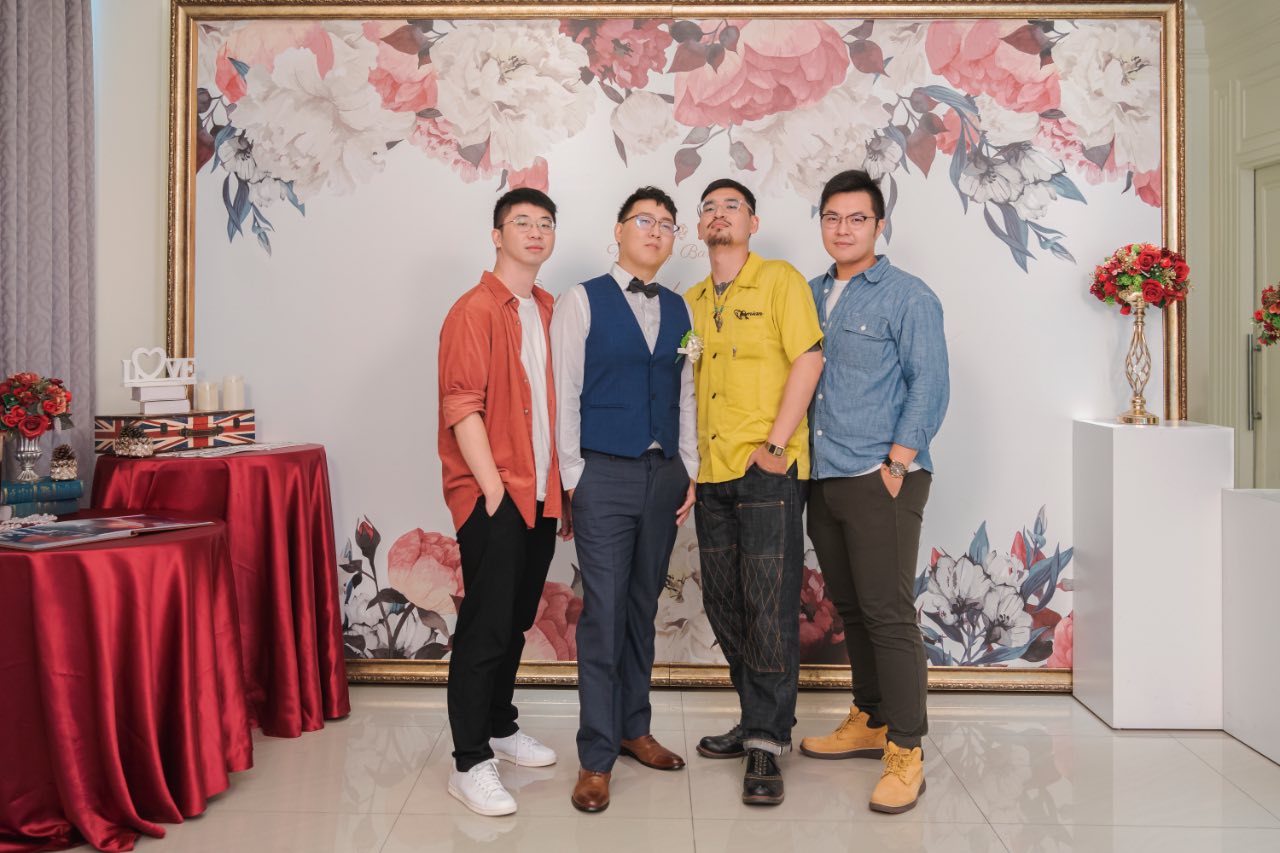 婚禮現場四位好友合照，背景是花卉佈景，畫面乾淨明亮。
