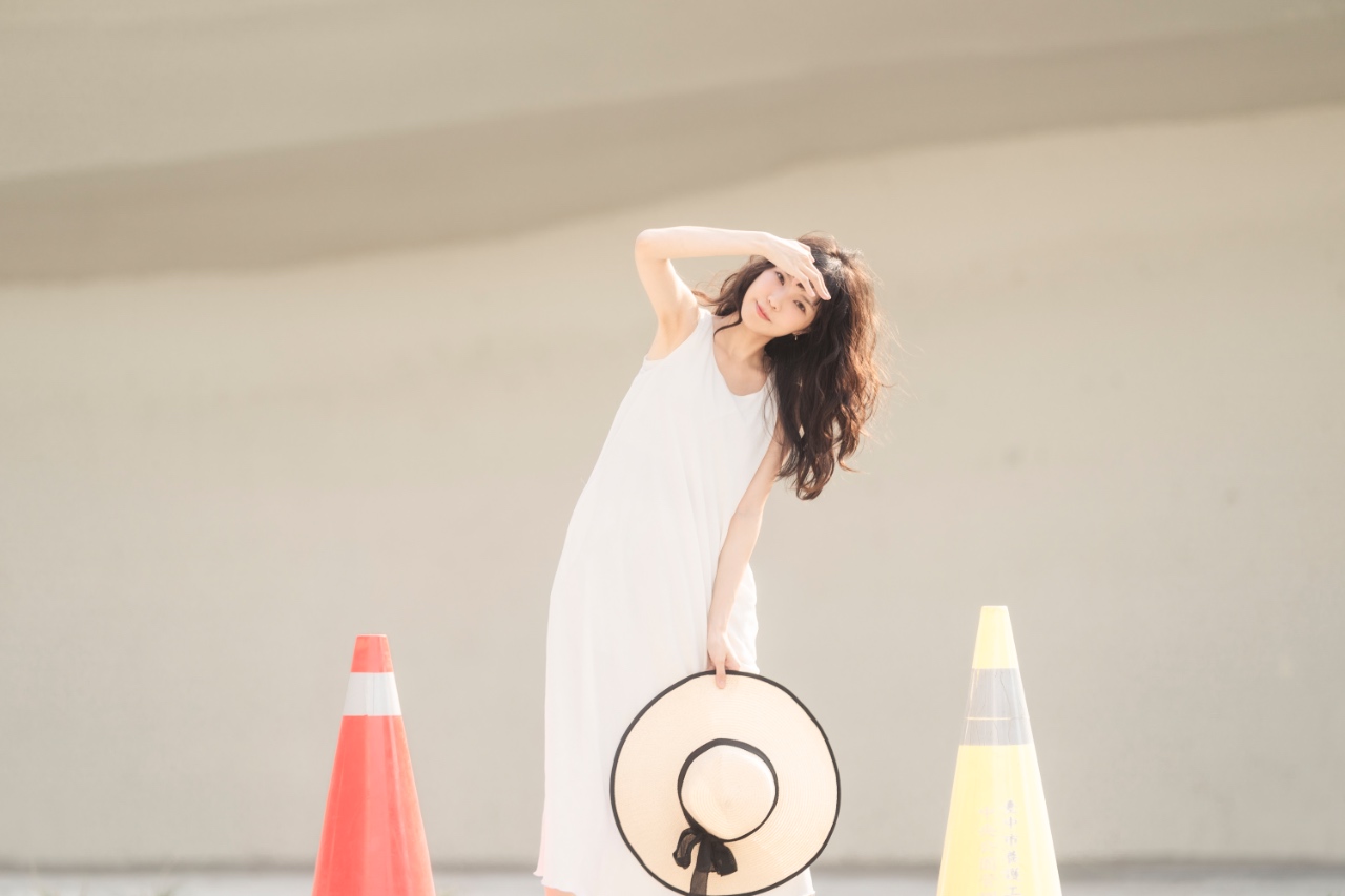 站立姿勢手舉到頭旁邊頭部傾斜拿草帽的拍照姿勢