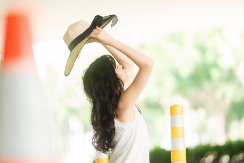 女生雙手高舉草帽仰頭看帽子的人像拍照姿勢示範