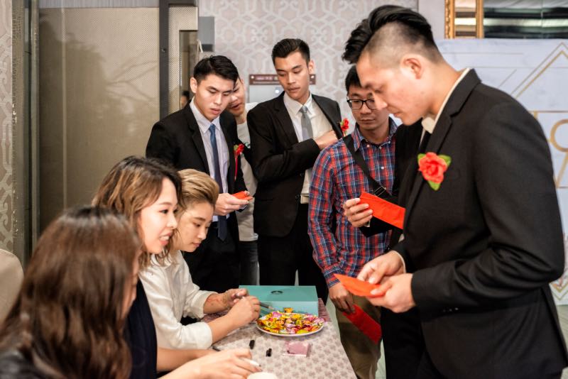 婚禮現場簽到桌，工作人員協助賓客登記、發放紅包，多人同時在場的忙碌畫面